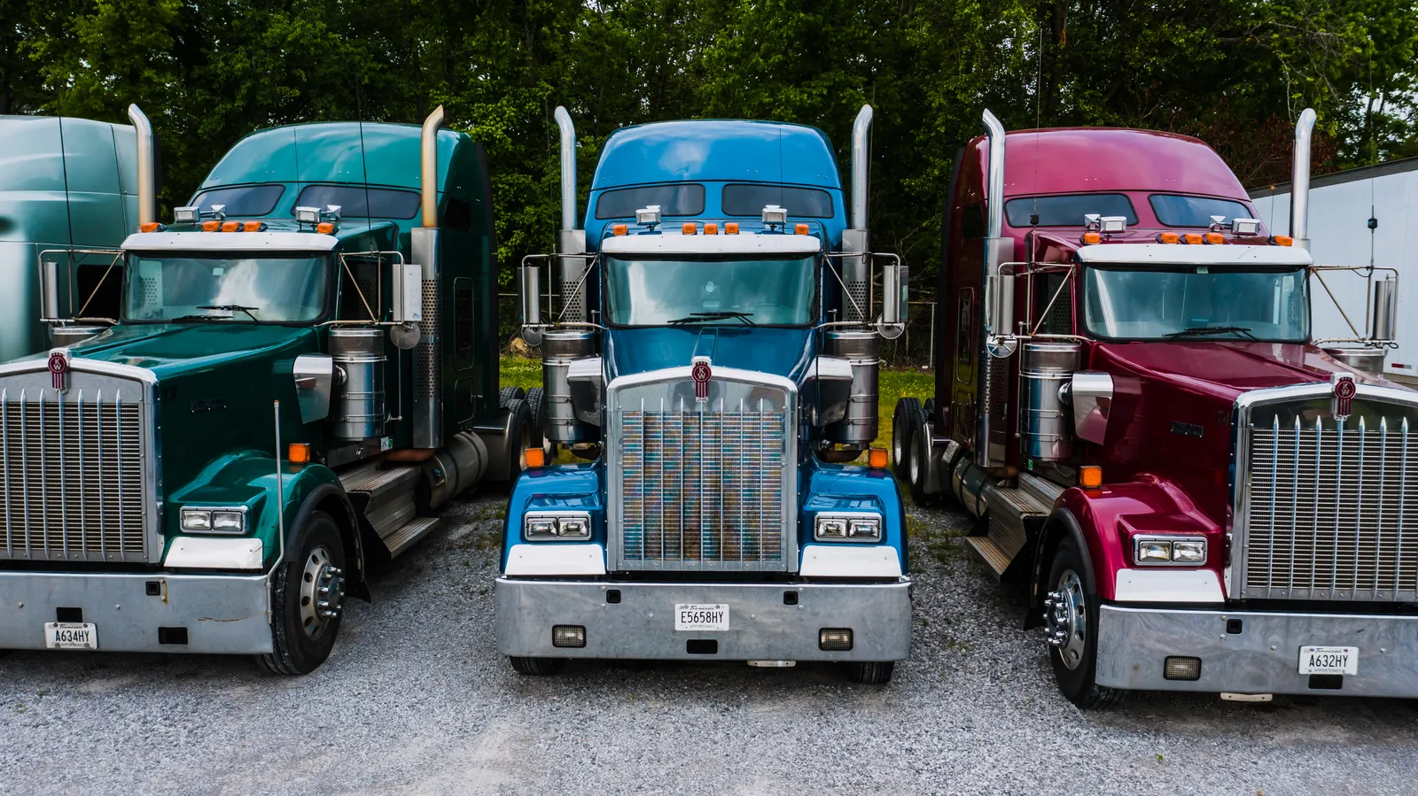 Three American semi-trucks parked side by side in a Tennessee truck yard.